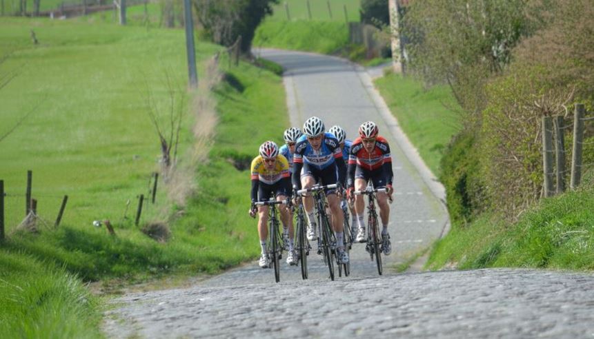 Cyclistes en pleine ascension d'une route pavée de campagne.